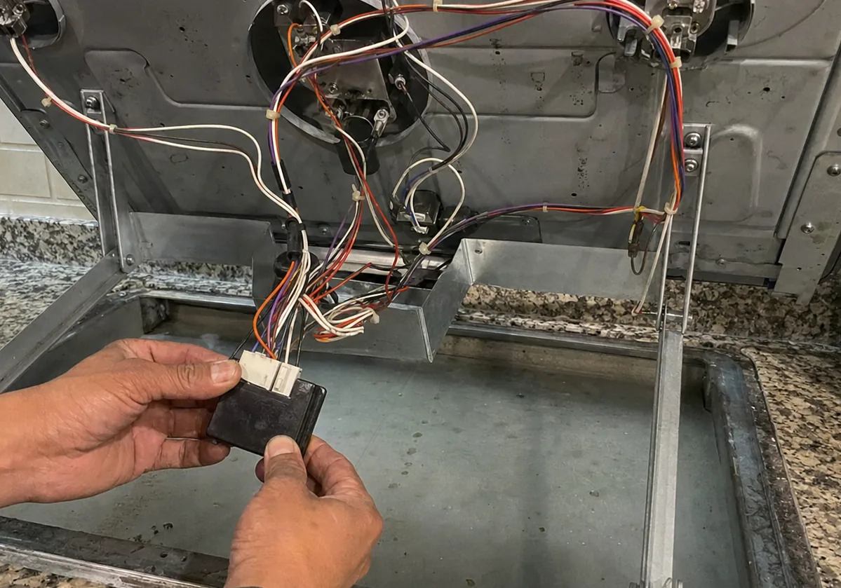 Centre crop of the spark module test, a hand steadying the module while the other holds a probe against its terminals.